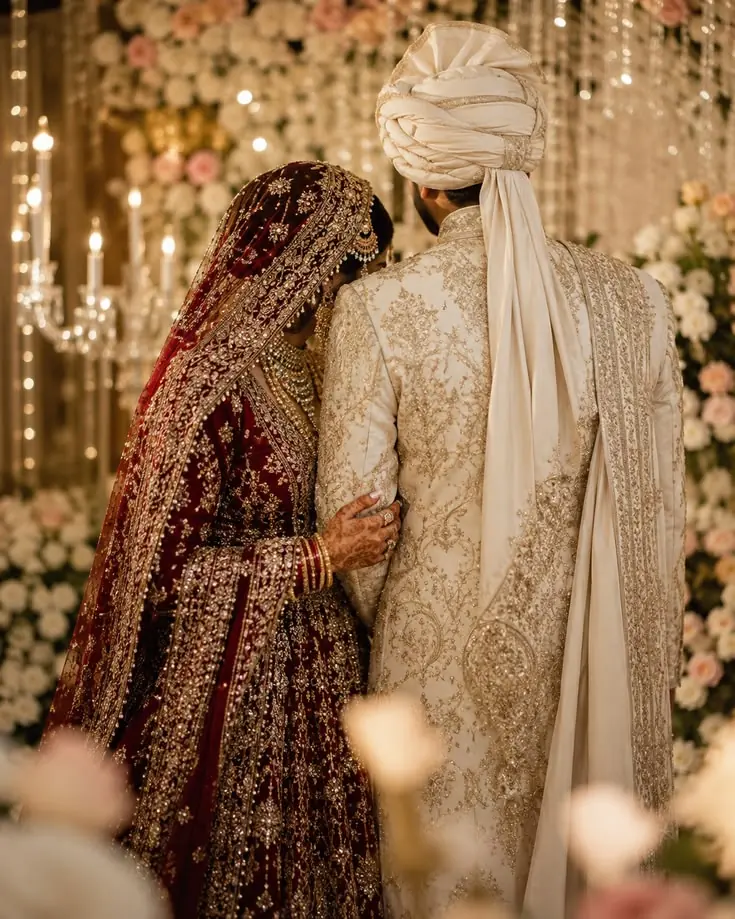 Bride in red dupatta and groom in sherwani, seen from behind